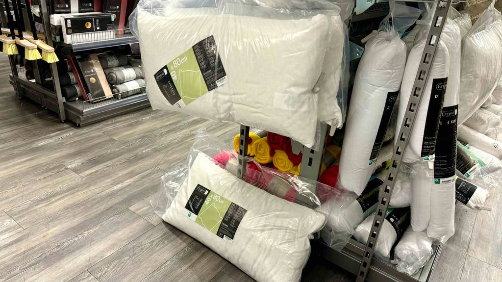 Mehrere Visco-Kissen hängen zum Testen mit anderen Produkten an einem Regal.