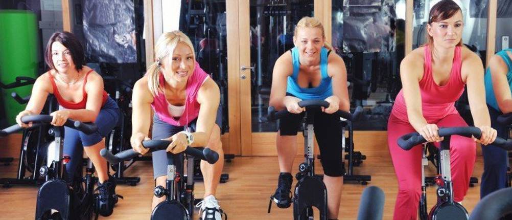 Frauen trainieren im Fitnessstudio auf dem Fahrradergometer