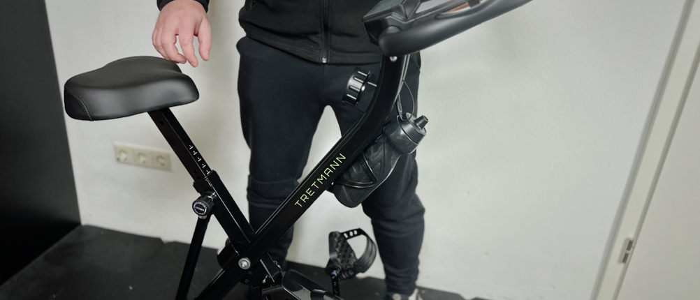 Ein Mann steht neben dem Ergometer von Tretmann.