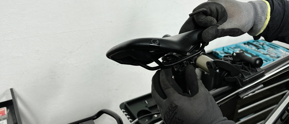 Der Ergon SMC Sport wird in einer Werkstatt mit einem Innensechskantschlüssel an der Sattelstütze befestigt. Zwei behandschuhte Hände justieren den Winkel.