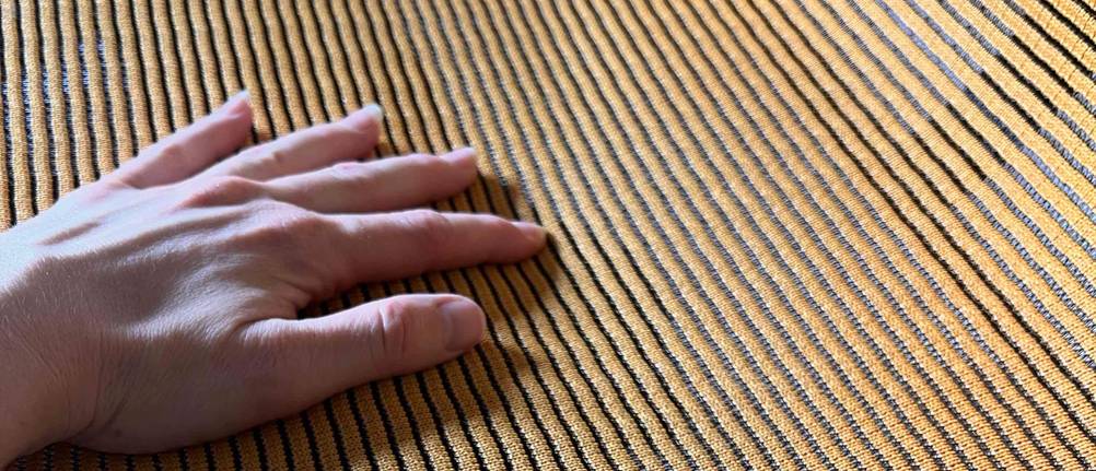 Eine Hand liegt auf einem ergonomischen Bürostuhl mit Netzgewebe im Test.