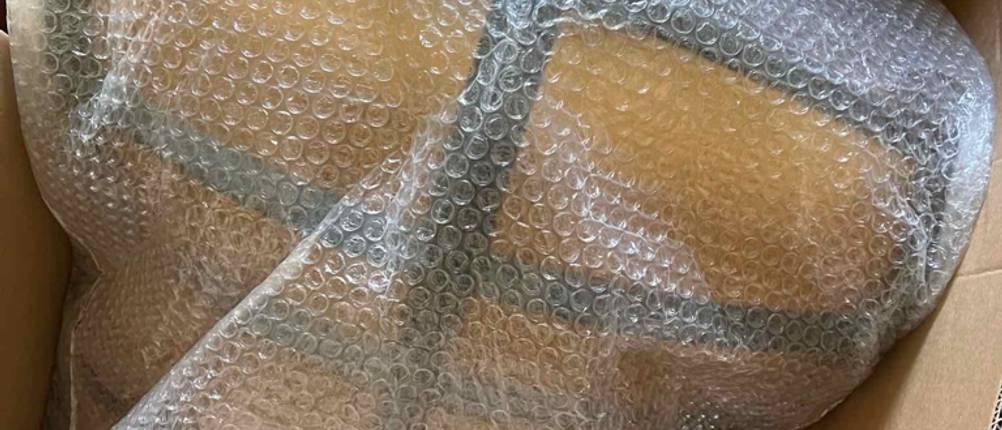 Man sieht einen in Luftpolsterfolie verpackten ergonomischen Bürostuhl.
