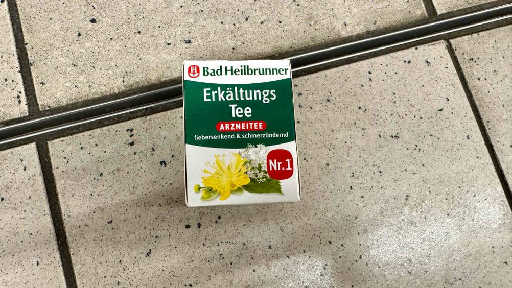 Auf einem Fließenboden liegt eine Packung des getesteten Erkältungstees.