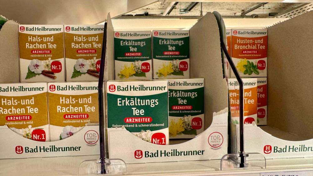 Mehrere Packungen des getesteten Erkältungstees in einem Regal neben anderen Produkten stehend.