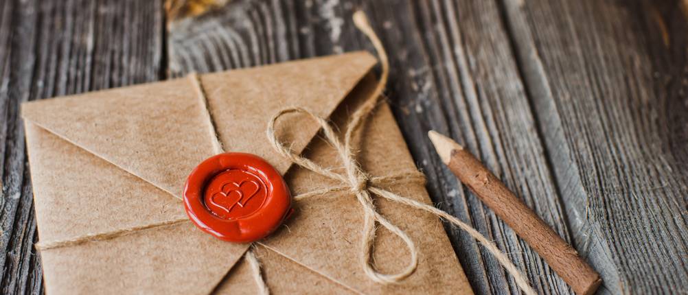 Erlebnisgeschenke im Test: Neben einem selbst gemachten Brief mit Siegel liegt ein Holzstift.