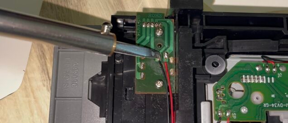 Ein Ersa 30 S Lötkolben wird an eine kleine Lötstelle auf einer Platine in einem geöffneten Elektronikgehäuse geführt. Mehrere Drähte und Bauteile sind sichtbar verbunden.