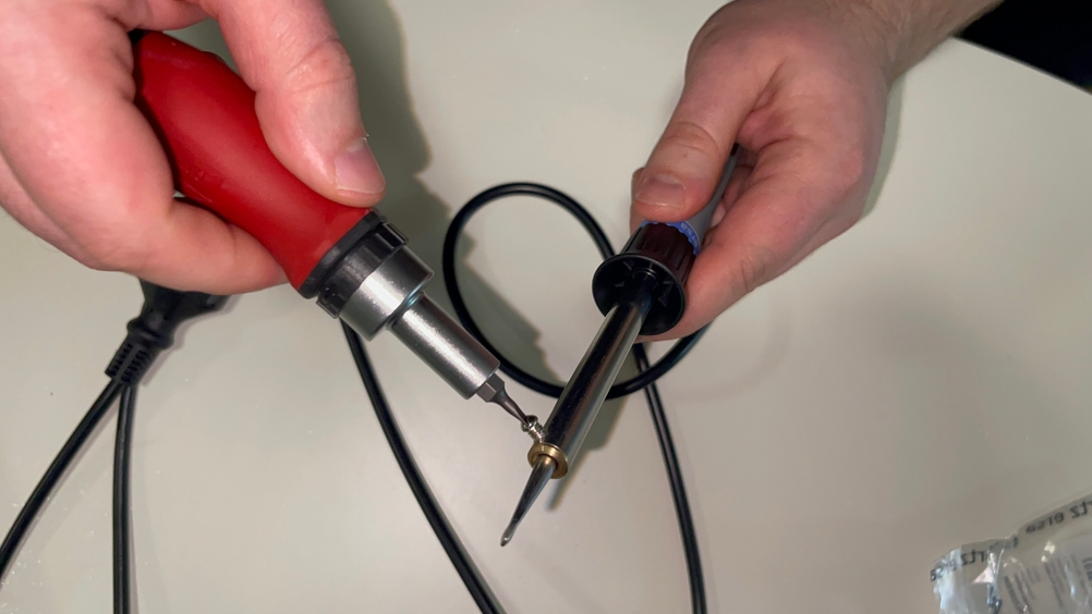 Zwei Hände halten einen Ersa 30 S Lötkolben und ein weiteres Werkzeug zur Lötspitzenbearbeitung.