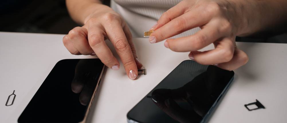 Eine Frau tauscht ihr Smartphone gegen ein anderes aus und setzt die SIM-Karte neu ein.