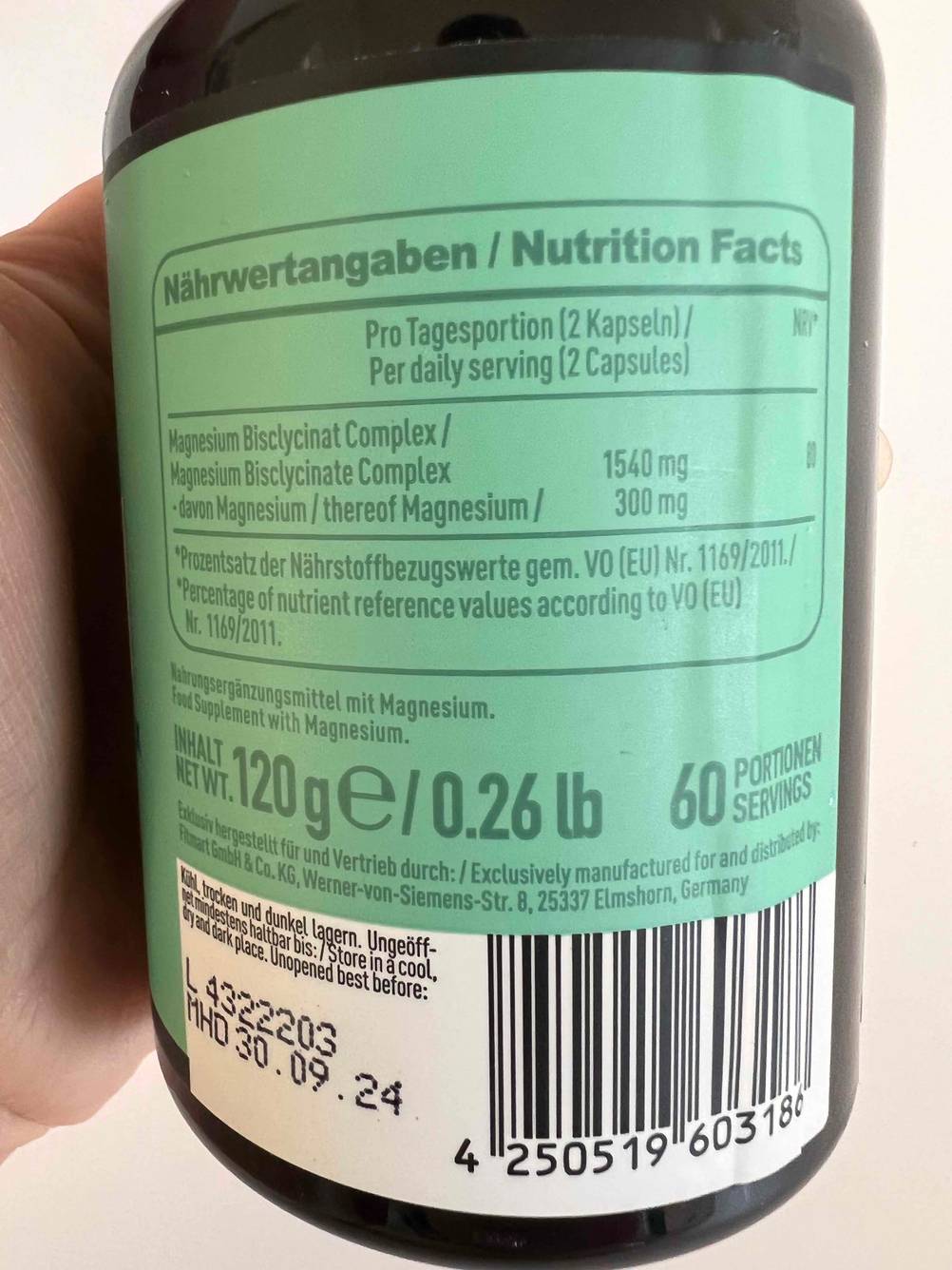 Nahaufnahme eines hellgrünen Etiketts mit Nährstoffangaben auf einem Braunglas-Behälter mit hoch dosiertem Magnesium im Test.
