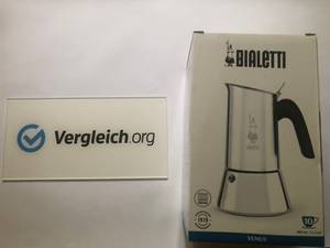 Bialetti New Venus Espressokocher aus unserem Test neben einem Vergleichschild