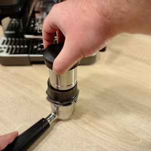 Mit Hilfe eines Tampers wird Kaffeepulver im Siebträger der Ninja-Espressomaschine verdichtet.