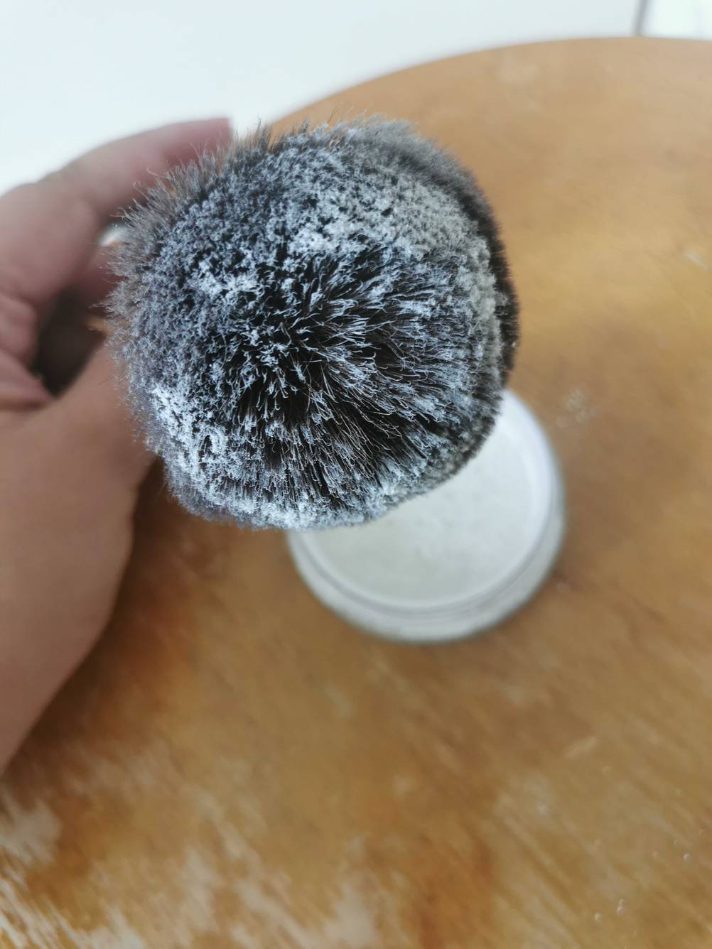 Eine Hand hält einen Pinsel voll mit Puder zum Testen.