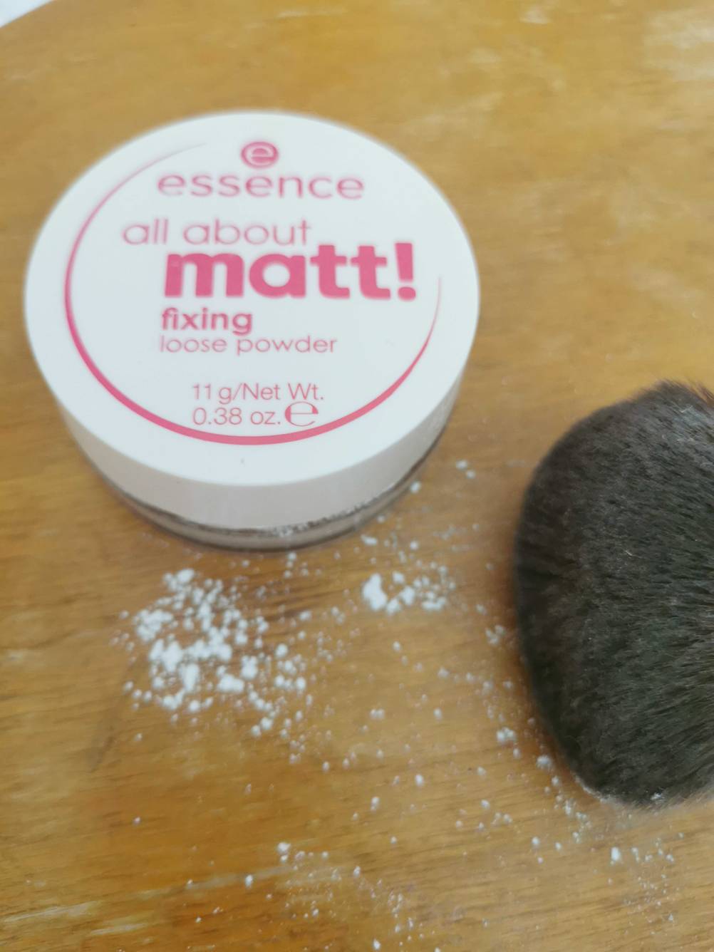 Vor dem Tiegel liegt etwas getesteter loser Puder und ein Pinsel daneben.