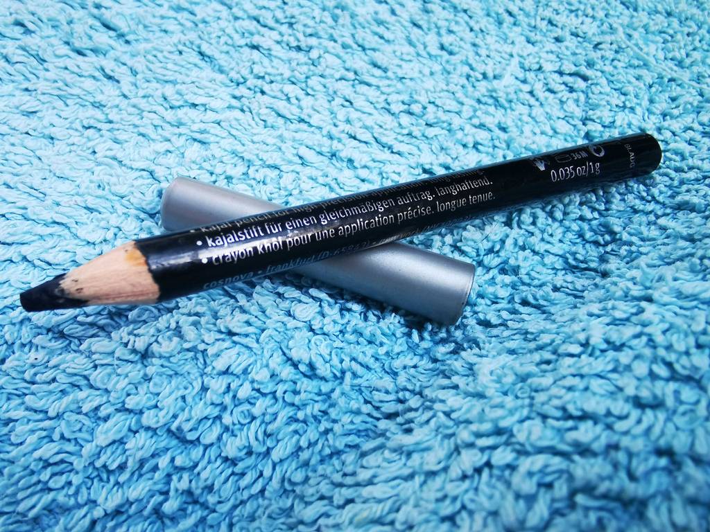 Kajalstift Test: Ein schwarzer Stift liegt oberhalb seiner Abdeckung auf einem blauen Frotteestoff.
