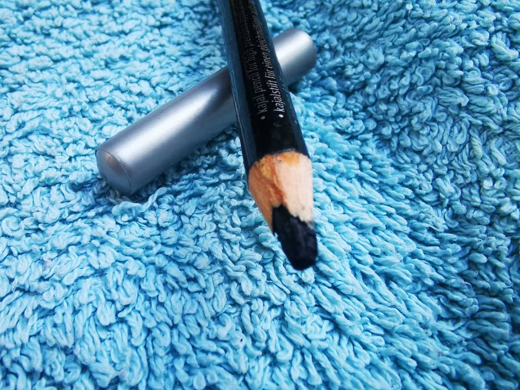 Kajalstift Test: Ein schwarzer Stift liegt, mit Fokus auf seine Spitze, auf einem blauen Frotteestoff.