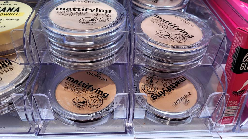 Mehrere Dosen inklusive Essence Puder im Test stehen nebeneinander auf einem Verkaufsregal.