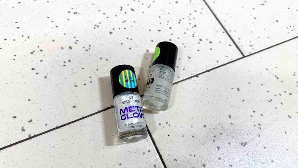 Zwei Fläschchen des getesteten Essence-Nagellacks liegen auf einem hellen Fließenboden.