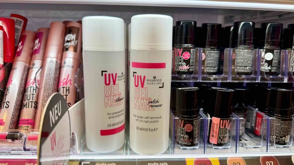 Nagellackentferner im Test: Mehrere Flaschen stehen zwischen anderen Produkten in einem Regal.