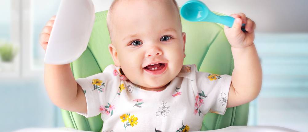 Baby isst mit Esslernbesteck.