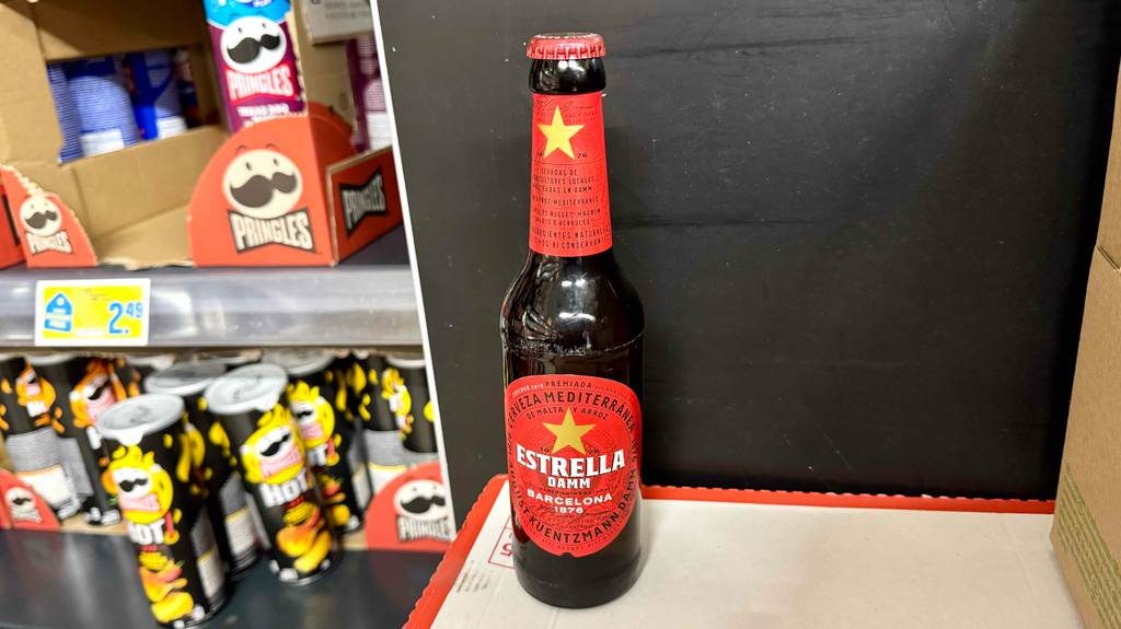 Im Test: Spanisches Bier in der braunen Flasche mit rotem Etikett steht neben einem Verkaufsregal mit salzigen Knabbereien.