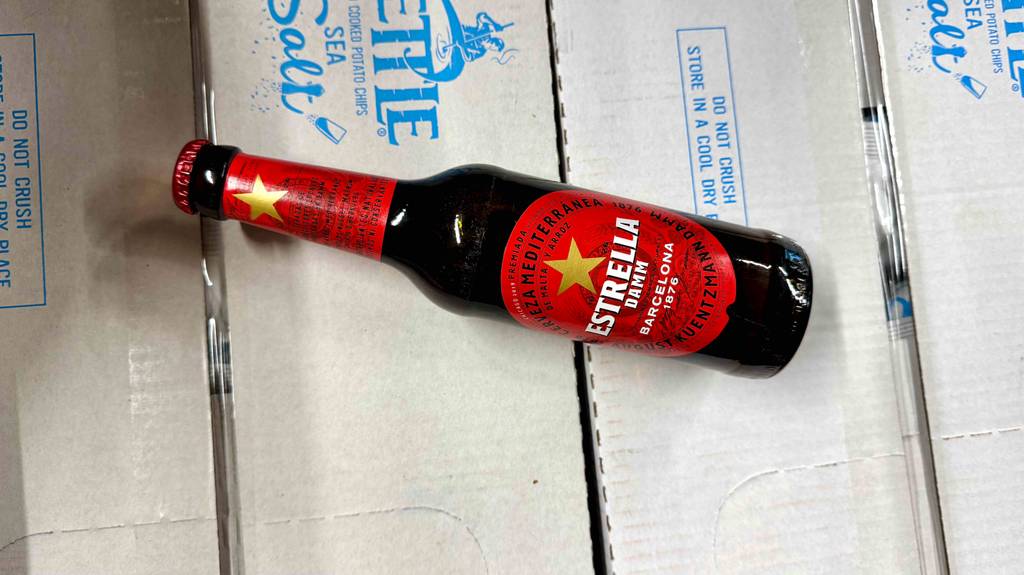 Getestet: Spanisches Bier in der braunen Flasche inklusive rotem Etikett liegt auf einem Karton.