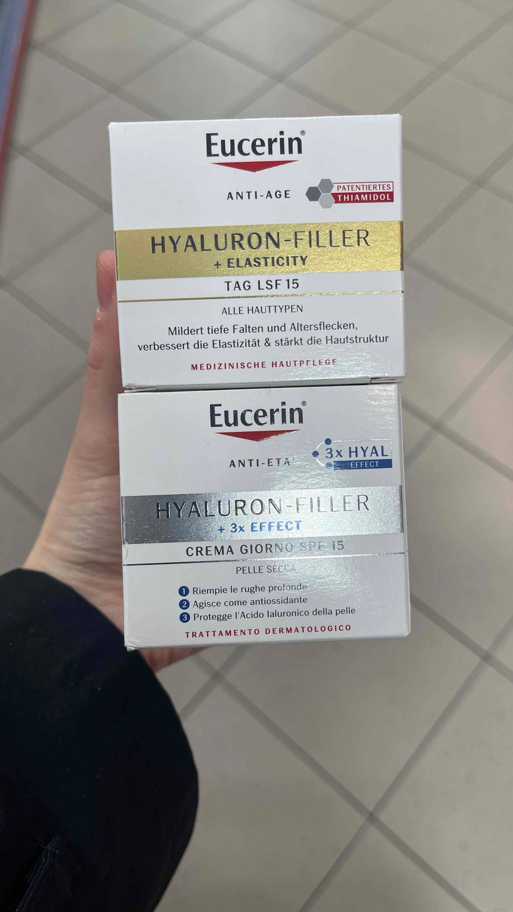 Eine Hand hält zwei Packungen Eucerin Hyaluron-Filler zum testen.