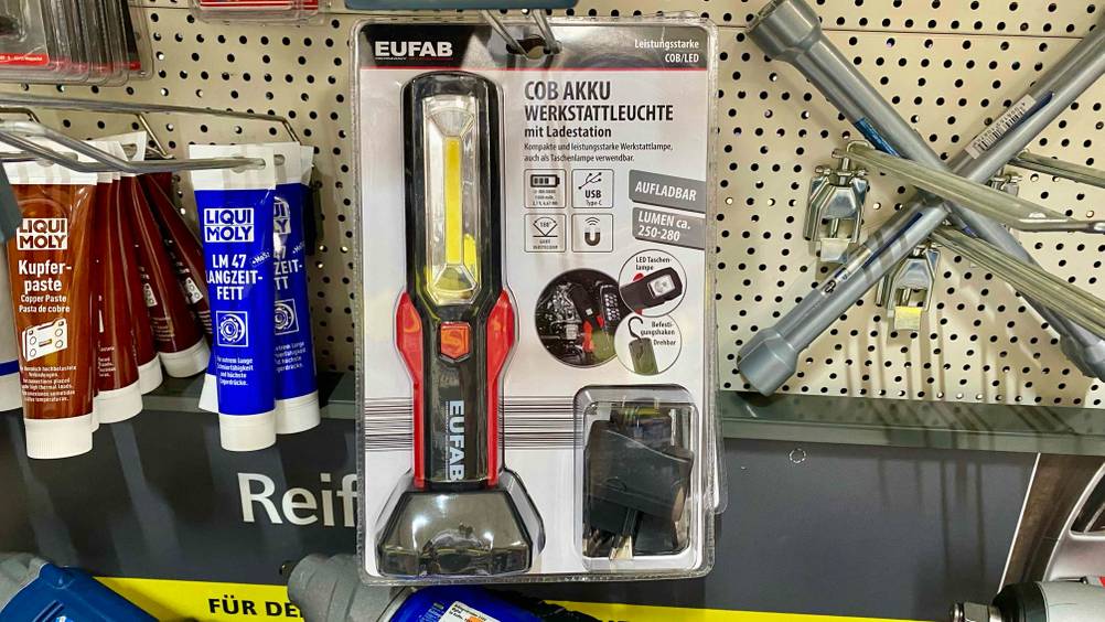 Im Test: Eine Werkstattlampe hängt neben anderen Produkten in einem Verkaufsregal.