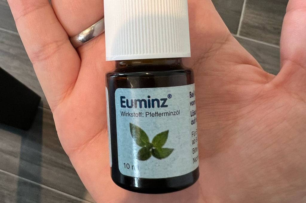 Pfefferminzöl-Test: Auf einer Handfläche liegt ein 10-ml-Flacon Pfefferminzöl von Euminz.