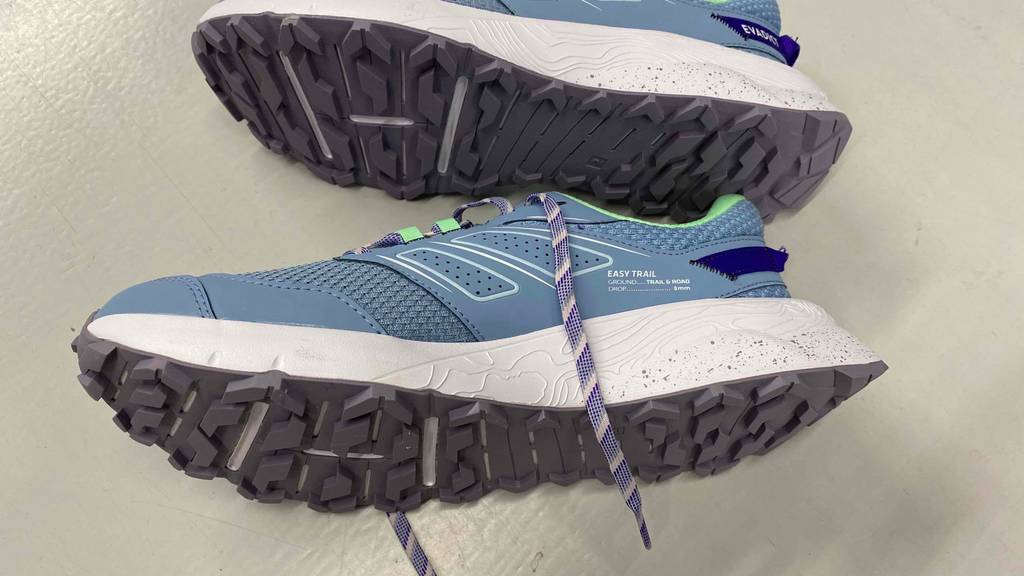 Im Test: Trailrunningschuhe für Damen in blau von Evadict liegen seitlich mit der Sohle nach vorn übereinander auf weißer Fläche.