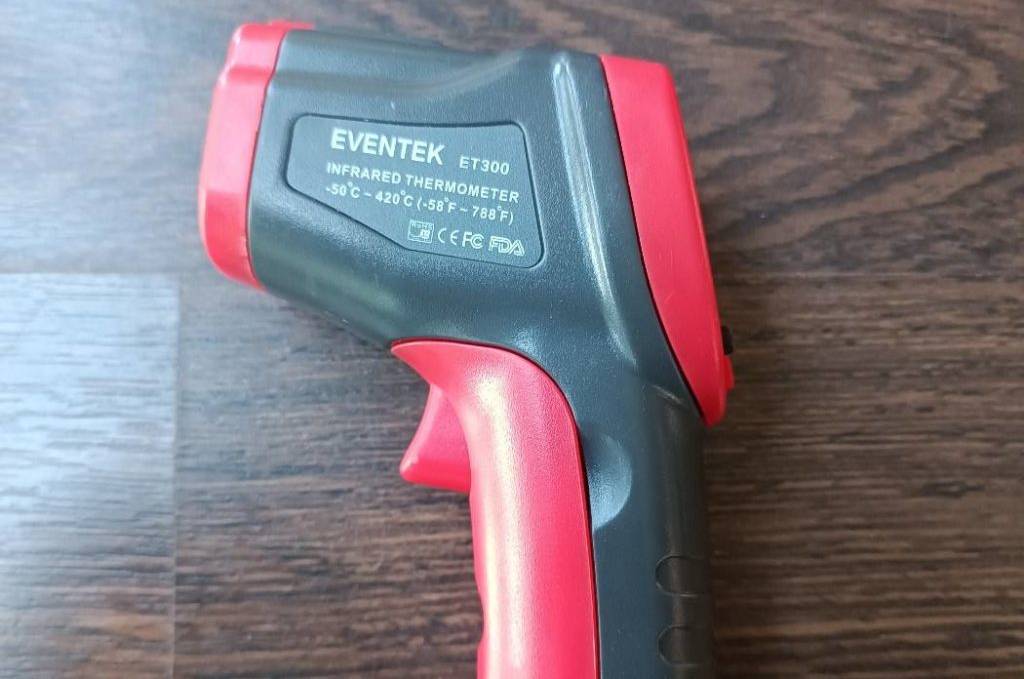 Infrarot-Thermometer getestest: Eventek-Modell in Rot-schwarz liegt auf einer Holzunterlage.