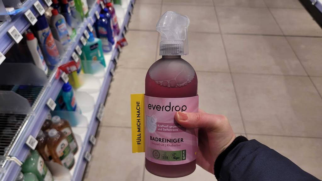 Badreiniger getestet: Eine Hand hält einen Pumpspender von Everdrop neben einem Verkaufsregal.