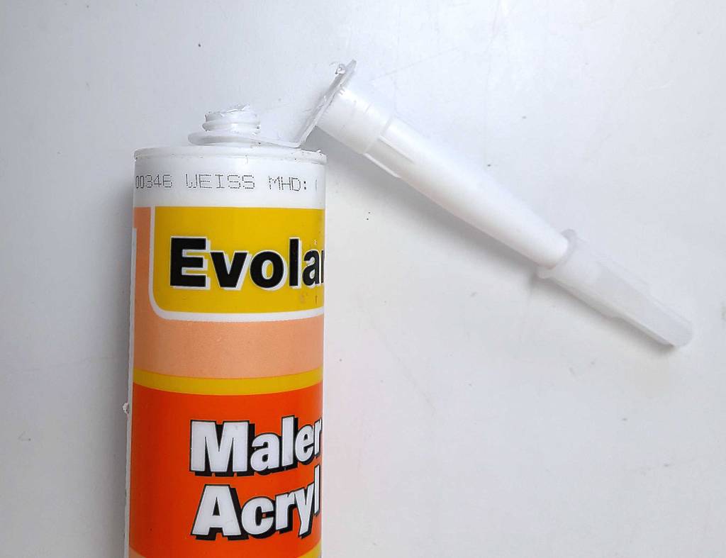 Detailansicht einer abgeknickten Spitze einer geöffneten Kartusche getesteter Acryl-Dichtstoff.