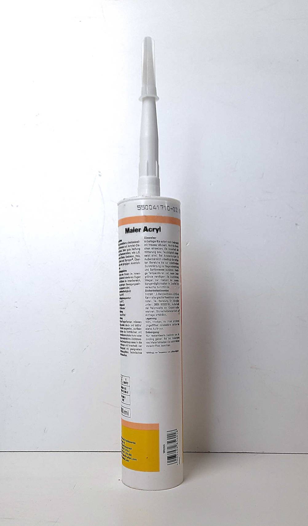 Eine Kartusche Acryl-Dichtstoff steht mit der Rückseite nach vorn zum testen vor einer weißen Wand.