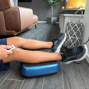 Eine Hand bedient die EvoSpark JTF017D-D mit einer Fernbedienung, während die Beine auf der Fläche liegen.