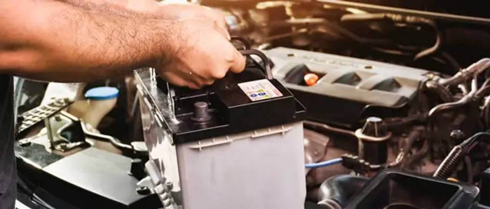 50-Ah-Autobatterie im Test: Eine Autobatterie wird in den Motorraum eines Autos gehoben
