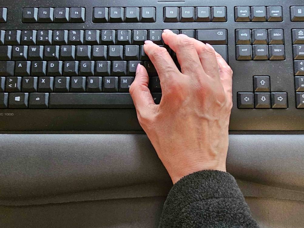Im Test: Eine Hand liegt auf einer Handballenauflage für die Tastatur und tippt auf der Tastatur.