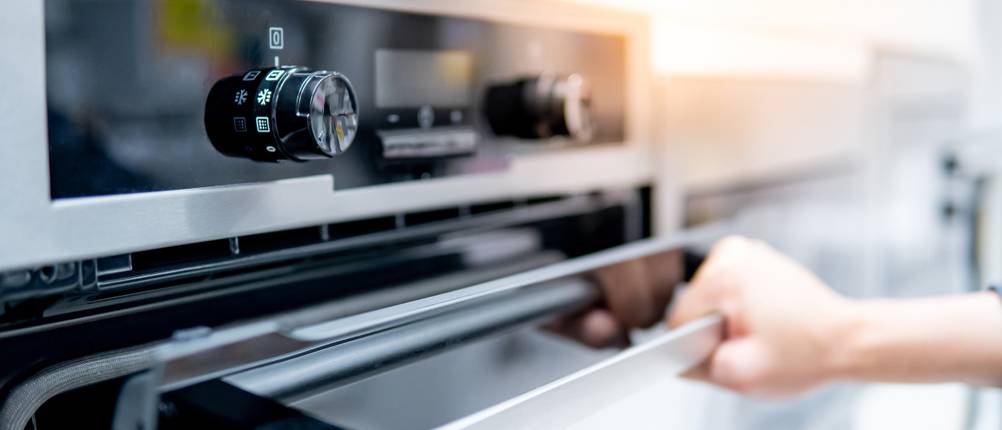 Exquisit-Backofen-Test: Die Front eines Backofens mit leicht geöffneter Klappe. Zwei Drehknöpfe und ein Display als Bedienelemente erkennbar.