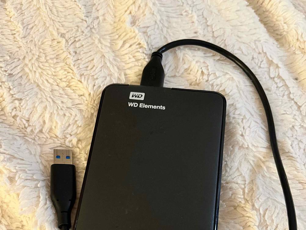 Getestet: Eine Externe Festplatte (1 TB) mit Logo auf einem hellen Stoff.