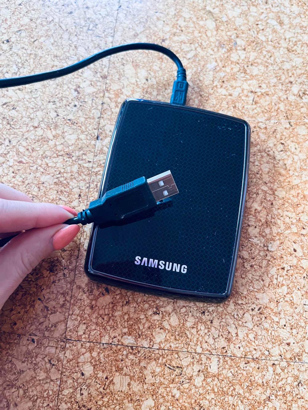 Externe Festplatte 3,5 Zoll getestet: Nahaufnahme des USB-Steckers von einer Hand nach oben gehalten, im Hintergrund die Platte.