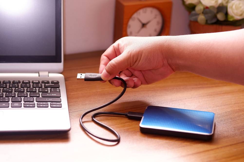 Externe SSD-Festplatte mit 1 TB im Test: Eine Hand steckt das Kabel einer SSD-Festplatte in einen Laptop.
