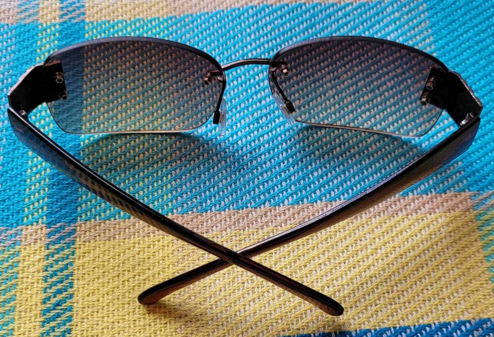 Eine getestete Damen-Sonnenbrille liegt mit überkreuzten Ohrbügeln und Sicht auf den inneren Nasensteg auf einer karierten Tischdecke.