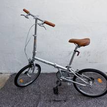Das aufgebaute FabricBike Folding Space Grey steht fahrbereit vor einer hellen Wand. Der Sattel ist ausgezogen, der Lenker montiert.
