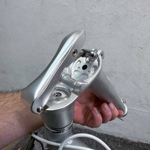 Das Bild zeigt den vollständig geöffneten Klappmechanismus am Lenker des FabricBike Folding Space Grey. Eine Hand hält das obere Rohrsegment.