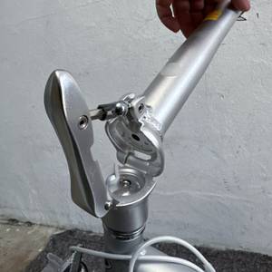 Der Lenker des FabricBike Folding Space Grey ist teilweise umgeklappt. Die Verriegelung ist geöffnet, eine Hand hält den Lenkergriff.