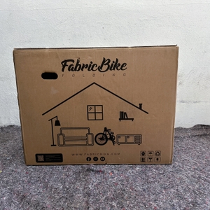 Der Versandkarton des FabricBike Folding Space Grey zeigt das Logo und eine stilisierte Wohnungsskizze mit Fahrrad.
