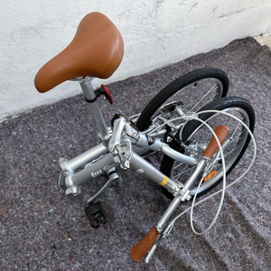 Auf dem Bild ist das vollständig zusammengeklappte FabricBike Folding Space Grey zu sehen. Das Rad steht kompakt gefaltet auf dem Boden.
