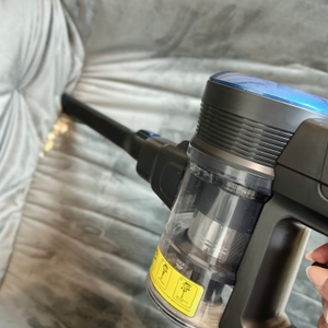 Der Fabuletta FSV001 wird mit einer schmalen Fugendüse auf einem grauen Polstermöbel verwendet. Krümel sind im Zwischenraum sichtbar.