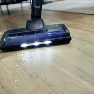 Die Bodendüse des Fabuletta FSV001 wird über einen Holzboden geführt. Vor der Düse befinden sich Sägespäne, die LEDs sind aktiv.