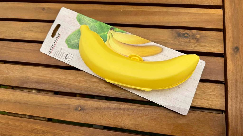 Eine gelbe Bananenbox im Test liegt mit ihrer Verpackung auf einer Holzoberfläche.