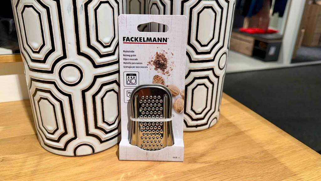 Im Test: Eine Muskatreibe steht in ihrer Verpackung vor zwei dekorativen Vasen.